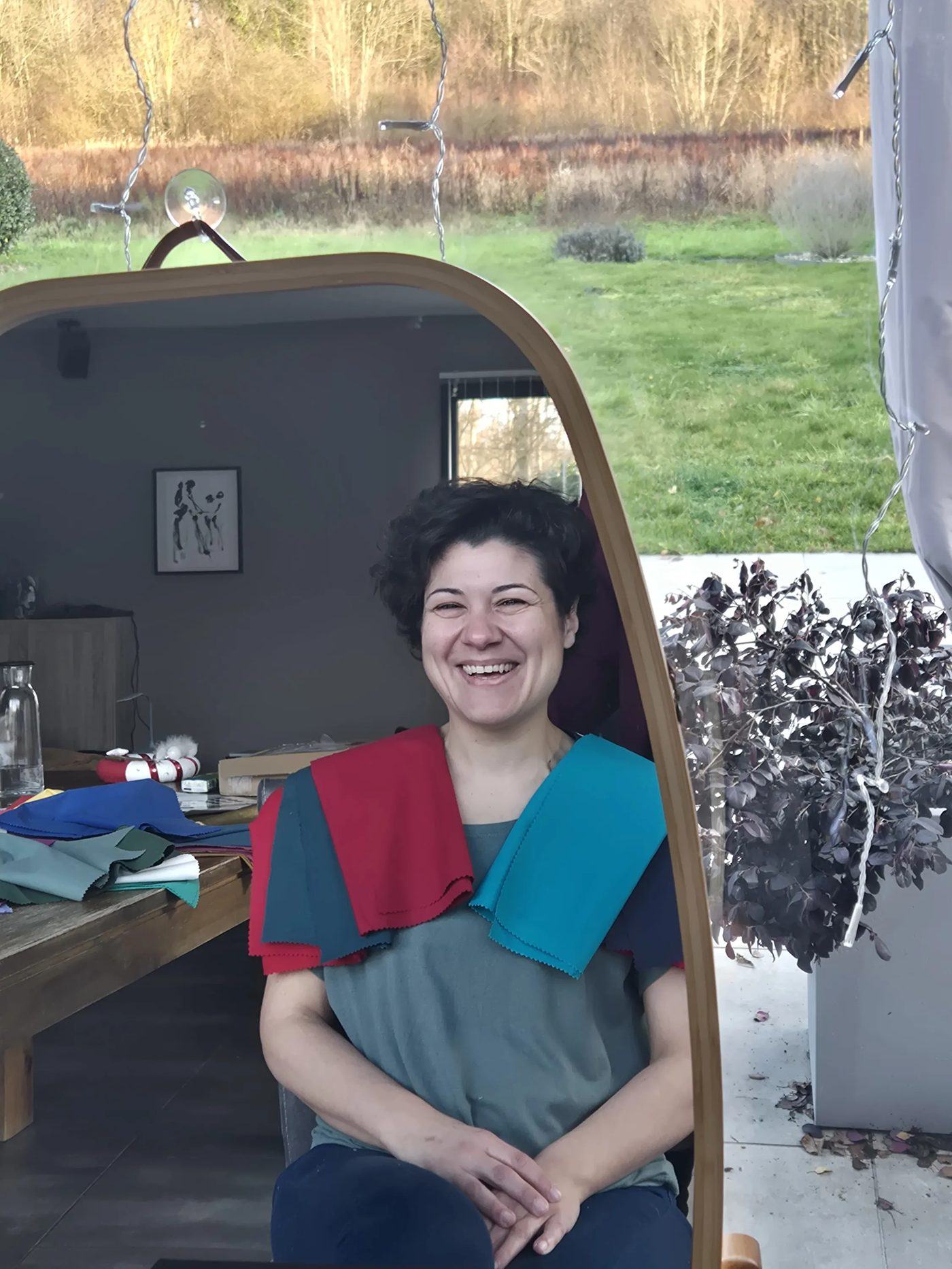 Cliente souriante, un tissu rouge et un tissu bleu drapés sur les épaules