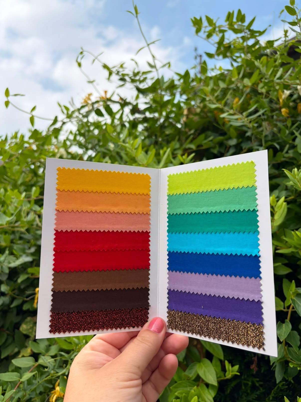 Nuancier de tissus colorés tenu devant un ciel lumineux