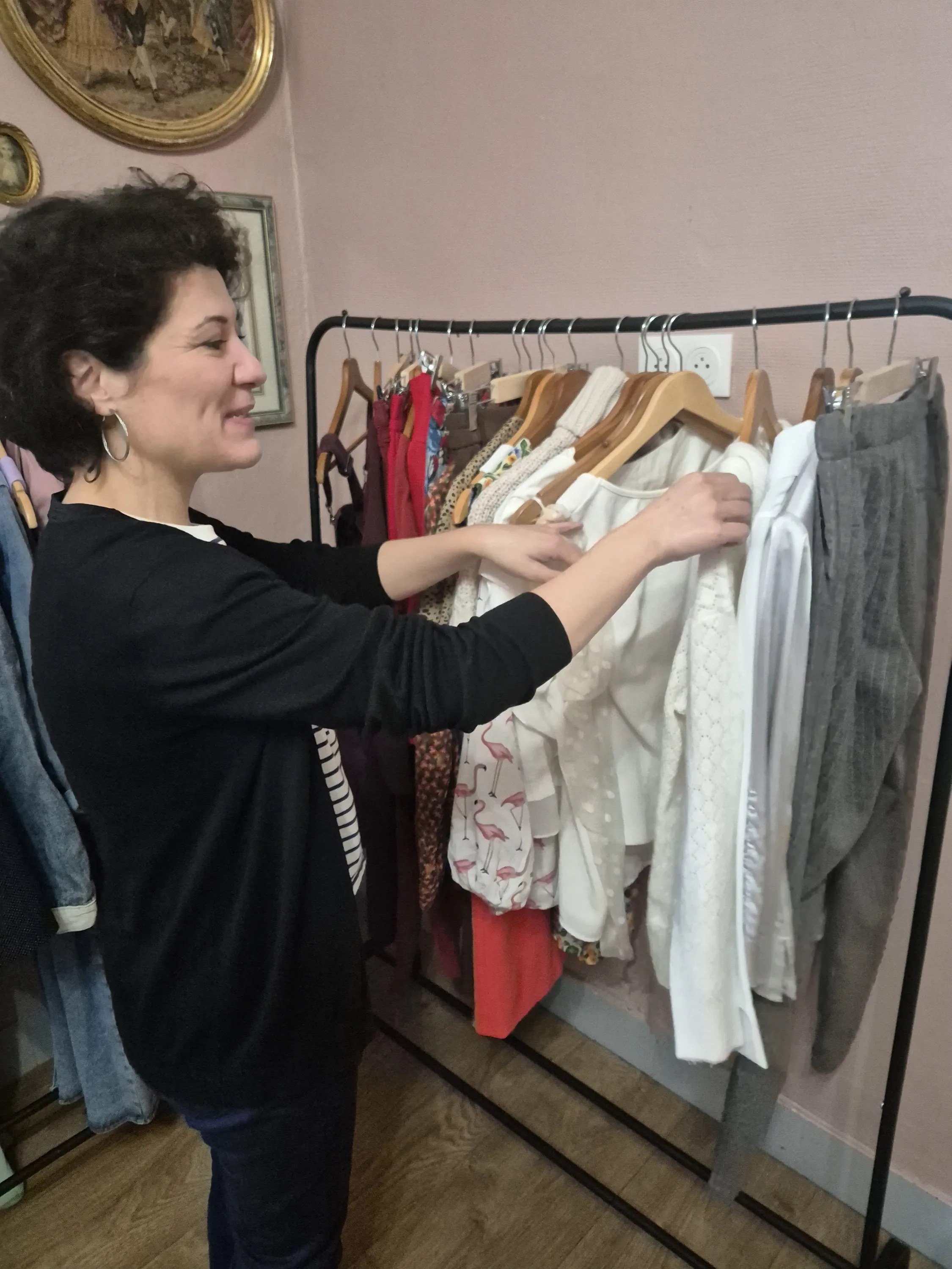 Sabrina sélectionnant des vêtements sur un portant en boutique